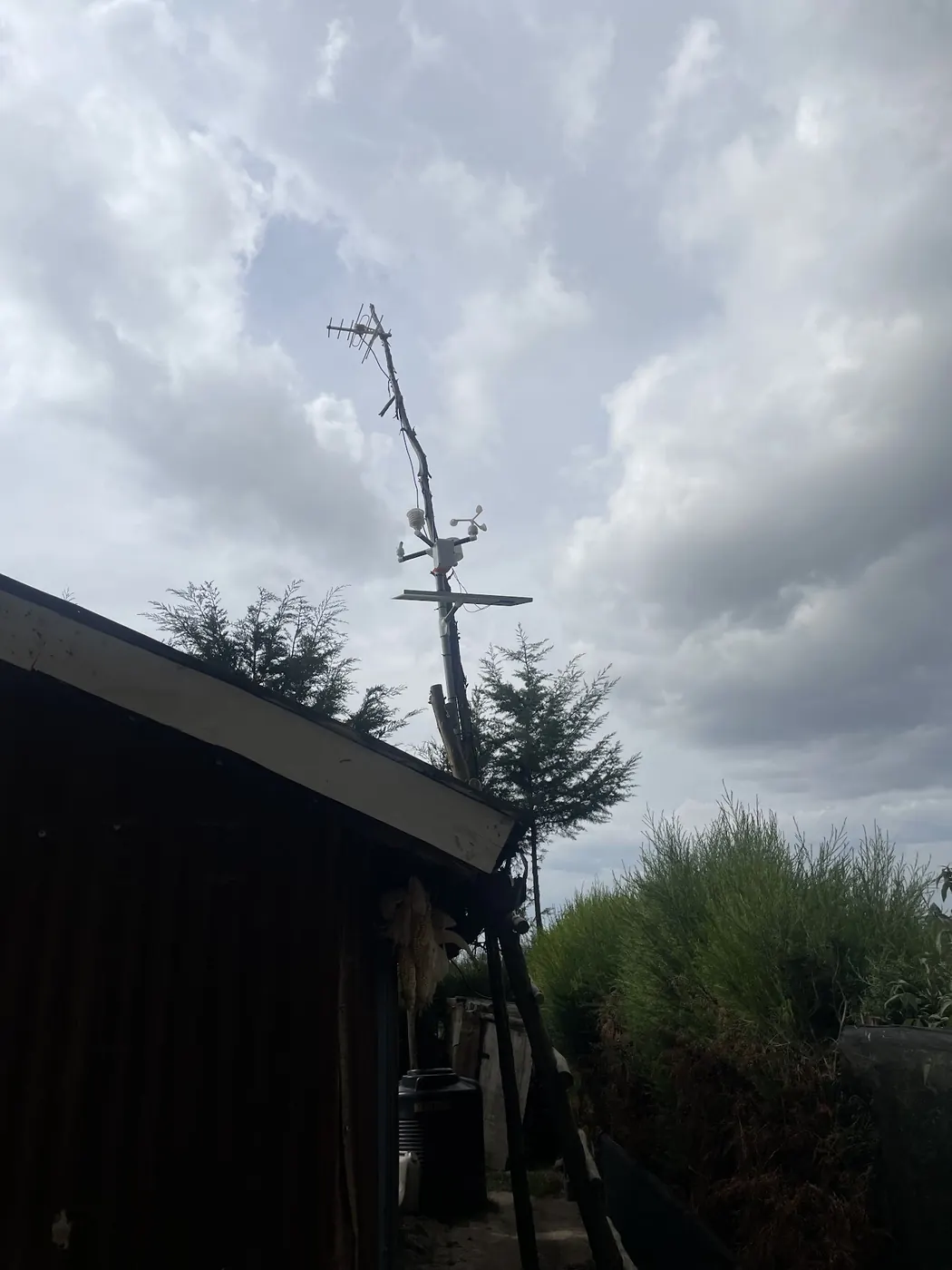 A weather station mounted above a farm shed roof