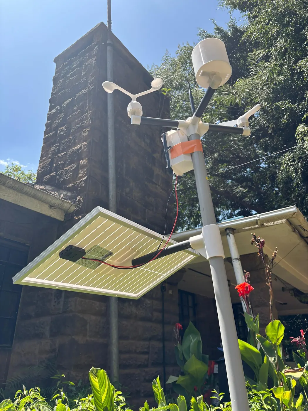 A weather station and its solar panel beside a stone house